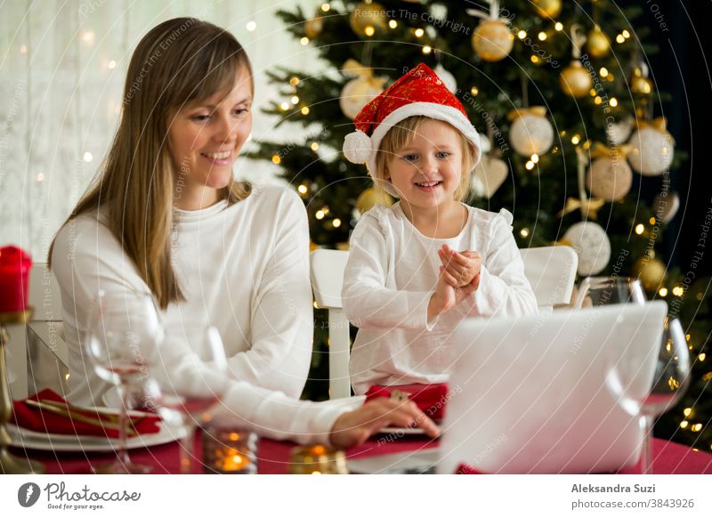Eine glückliche Familie mit einem Kind feiert Weihnachten mit ihren Freunden per Videoanruf per Webcam. Die Familie begrüßt ihre Verwandten am Heiligabend online. Neue normale virtuelle Veranstaltung