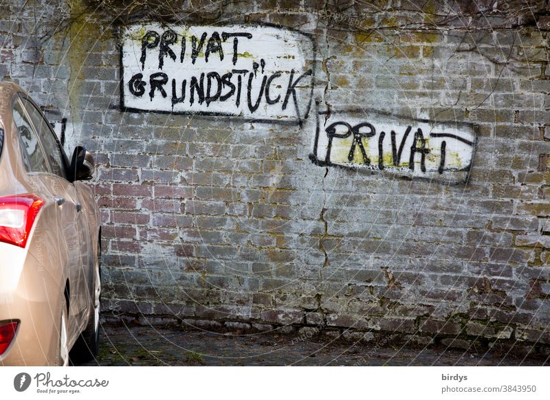 privatparkplatz vor einer alten Backsteinmauer mit individuellem Grafitti " Privat Grundstück , Privat " Privatgrundstück Schriftzeichen Hinweis parken PKW Auto
