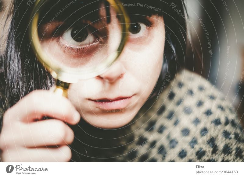 Junge Frau guckt durch eine Lupe genauer hin. hinsehen vergrößert Auge untersuchen prüfen schielen verzerrt Gesicht Linse Blick Detektiv Neugier beobachten