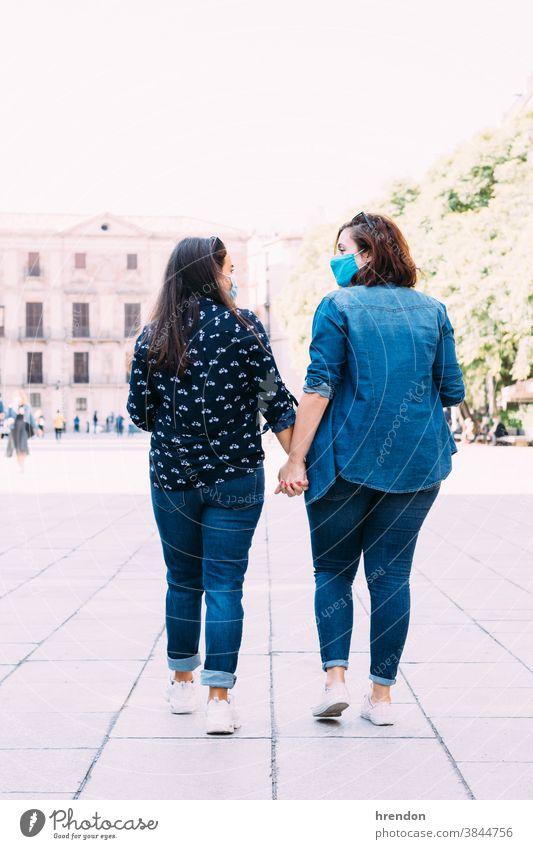 Paar Frauen mit Gesichtsmaske, die Hand in Hand gehen lesbisch Homosexualität Bund 19 laufen Liebe Händchenhalten Zusammensein romantisch Freundin Fröhlichkeit