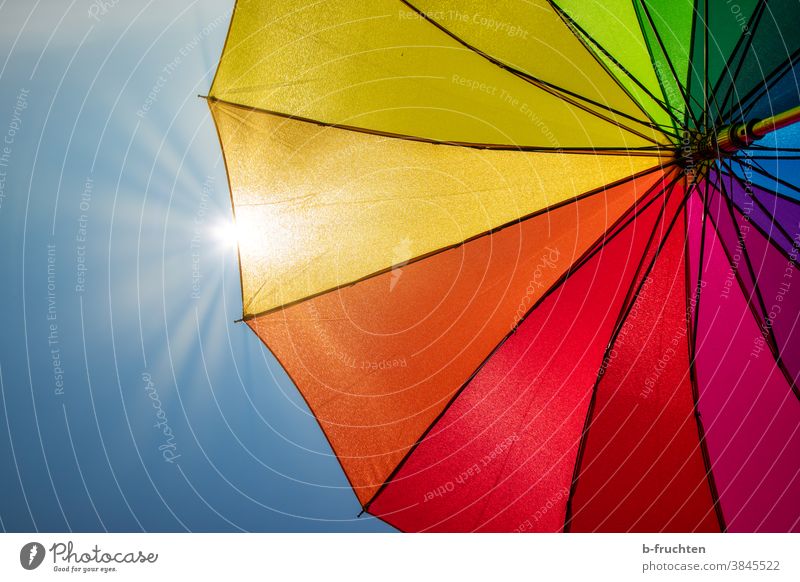 bunter Regenschirm bei Sonnenschein farbe regenbogenfarben himmel mehrfarbig Tag Licht Sonnenlicht Sonnenstrahlen Gegenlicht Sonnenschirm Schirm schützen