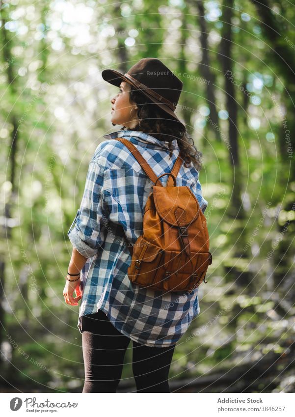 Reisende Frau mit Rucksack im Wald Fernweh reisen Ausflug Abenteuer bewundern genießen erkunden Stil kariertes Hemd Leder trendy Hut grün Wälder Natur Trekking
