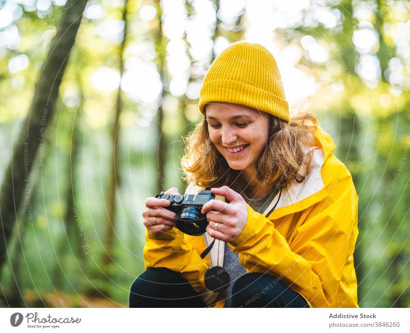 Fröhliche Frau mit Fotokamera im Wald Fotograf Reisender gelb Regenmantel Urlaub erkunden genießen heiter Tourist Feiertag reisen Lächeln Fernweh Ausflugsziel