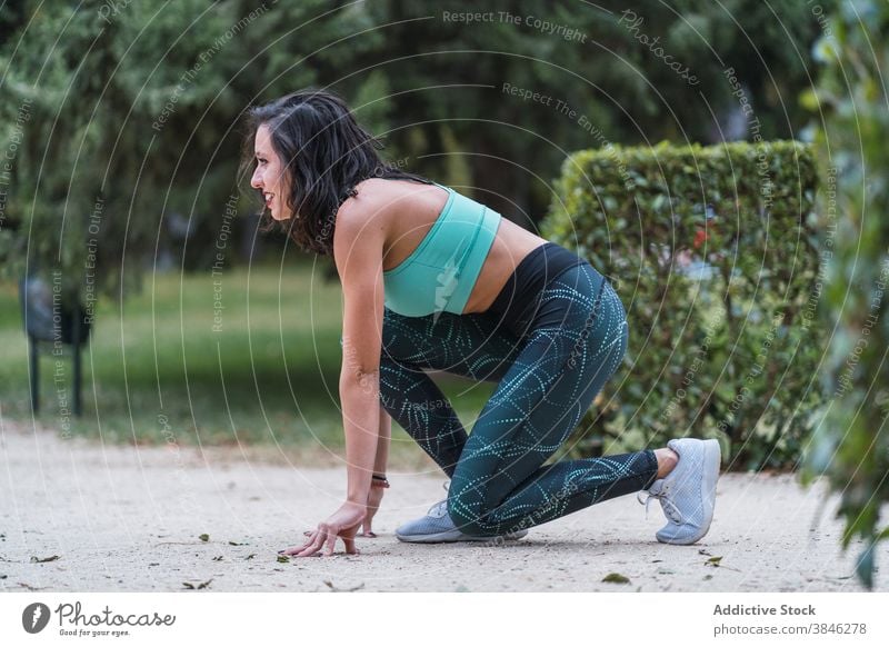 Sportlerin in gebückter Startposition im Park Kauerstart Läufer laufen Frau bereit Training positionieren Gesundheit Athlet Fitness Sportbekleidung Übung