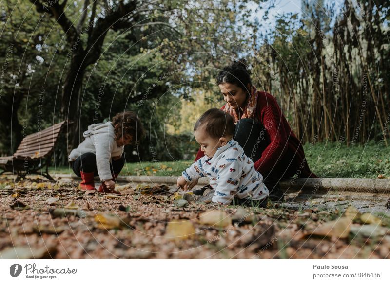 Mutter spielt mit zwei Kindern im Freien 0-09 Jahre 30-39 Jahre anhänglich authentisch Herbst fürsorglich lässig Kaukasier Farbe Neugier krause Haare Tochter