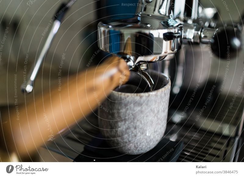 Siebträger an einer Siebträgermaschine, darunter ein Kaffeebecher aus glasiertem Ton. Ein Espresso wird zubereitet siebträger Café Nahaufnahme espressopulver