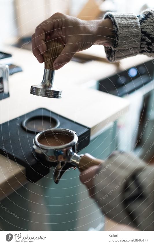 Barista mit Wolljacke drückt mit einem Tamper das Espressopulver in den Siebträger Kaffee Café siebträger Frau vorbereiten Nahaufnahme Hand espressopulver