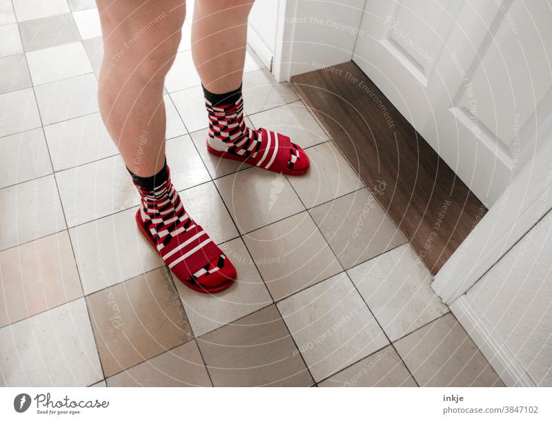 Blasse Beine stehen vor verschlossener Tür. Karierte Socken in gestreiften Badelatschen. Farbfoto Innenaufnahme Junge jungerMann Tag Raum Flur Zimmertür warten