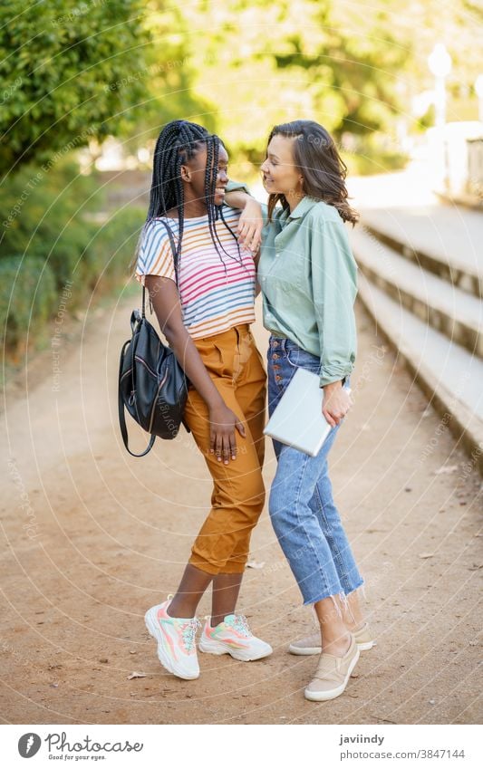 Zwei multiethnische Frauen posieren zusammen mit farbenfroher Freizeitkleidung Freund Tablette digital Mädchen jung Lifestyle urban schön Gerät außerhalb lässig