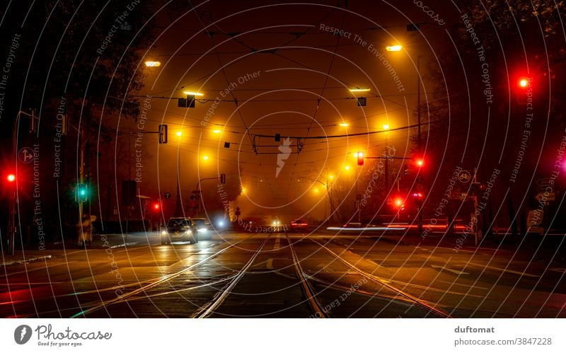 Langzeitbelichtung einer Kreuzung bei Nacht Ampel draußen Stadt Licht verschwommener hintergrund Abend Nachtleben Straße Bäume PKW Nebel Mobilität