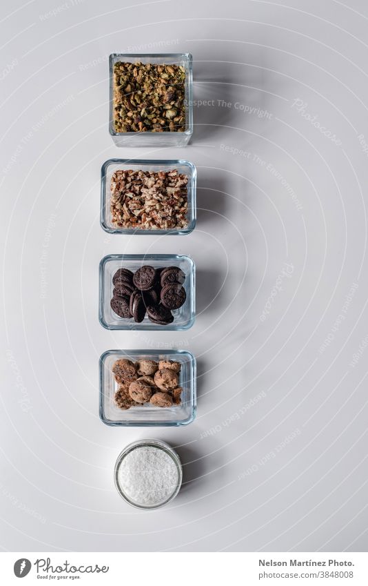 Reihe von Zutaten in kleinen Behältern mit Pistazien, Nüssen, Keksen und getrockneter Kokosnuss. Essen zubereiten Küchenchef roh weiß Tisch Zusammensetzung