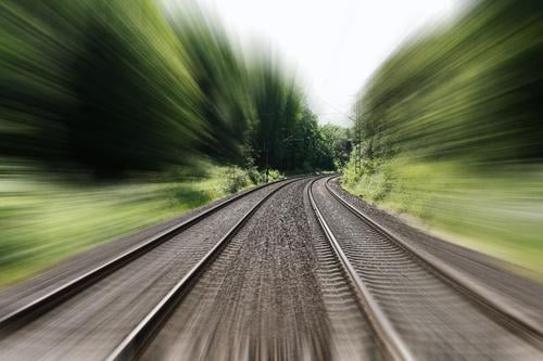Bahngleise mit Bewegungsunschärfe Geschwindigkeit Unschärfe Schiene Eisenbahn reisen schnell Zug Reise Transport Verkehr Urlaub Landschaft Natur Bäume