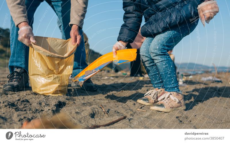 Freiwillige beim Putzen des Strandes Umweltbewusstsein Reinigen unkenntlich Enkelin Großvater abholend Müll Hilfe Müllsäcke Freiwilligenarbeit Einweghandschuhe