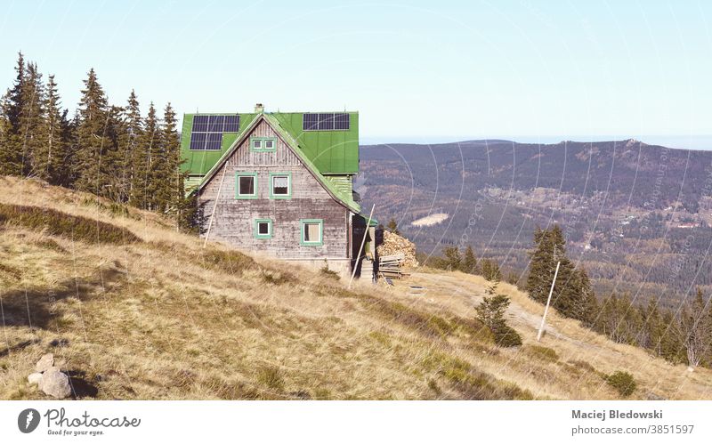 Retro-getontes Bild einer Berghütte mit Sonnenkollektoren auf dem Dach. Berge u. Gebirge Hütte Wartehäuschen Hügel Natur Landschaft retro Himmel Herbst