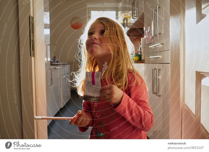 Kleines kaukasisches Mädchen hält Schild und Bleistift in der Hausküche Kind spielen blond Kaukasier Lifestyle Frau im Innenbereich natürliche Beleuchtung