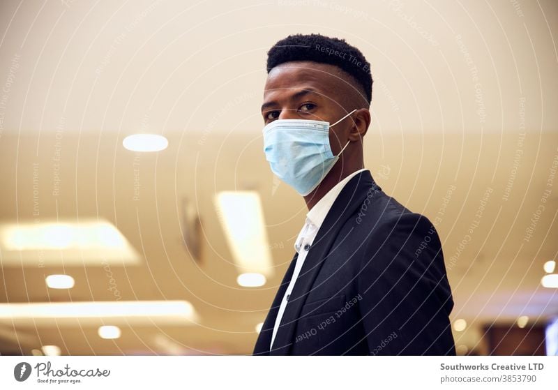 Porträt eines jungen Geschäftsmannes mit Maske, der während einer Gesundheitspandemie in einem modernen Büro steht Business Gesichtsmaske Gesichtsbedeckung