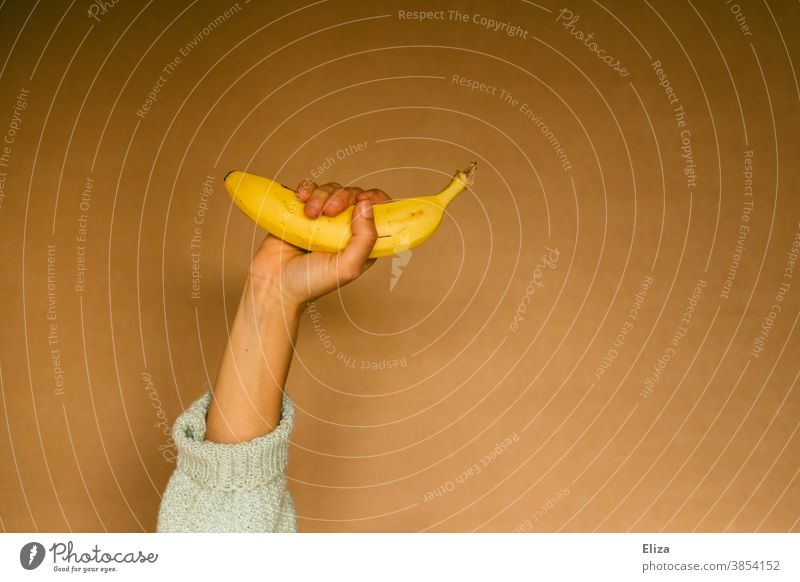 Eine Person hält eine Banane noch Hand obst gesund Gesunde Ernährung gelb halten Frau Neutraler Hintergrund
