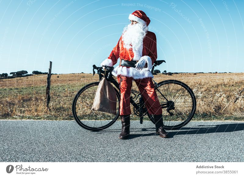 Weihnachtsmann in der Nähe von Fahrrad auf der Straße auf dem Lande Landschaft Tasche sich[Akk] entspannen Fahrbahn Fahrzeug Weihnachtsmütze männlich Vollbart