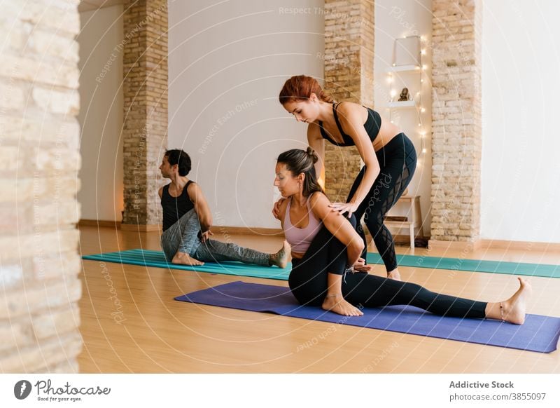 Trainer hilft Frau mit Sage Marichis Pose Frauen Yoga Dehnung Lektion Atelier Hilfsbereitschaft Ausbilderin Salbei Marichis Pose verdrehen jung passen schlank