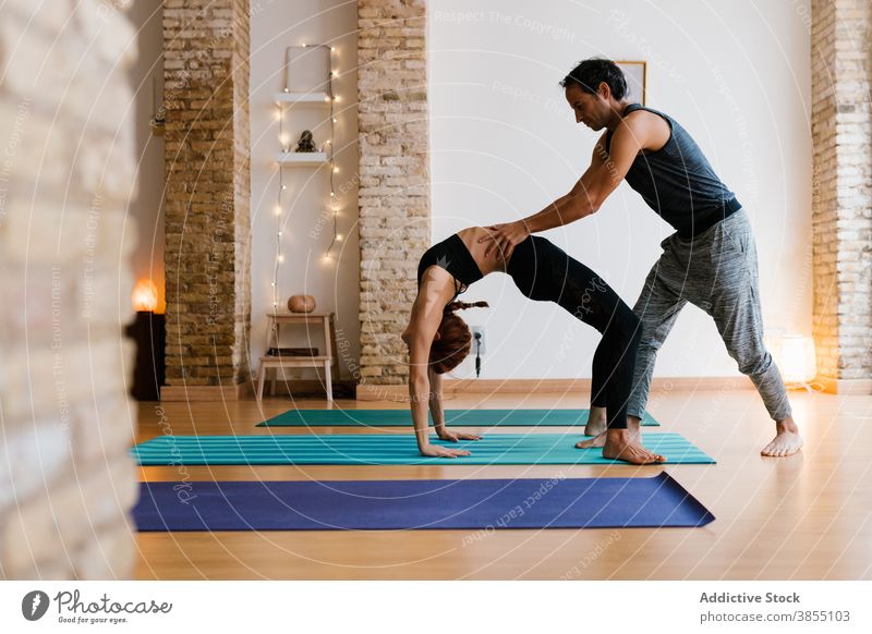 Mann und Frau tun Yoga zusammen Hilfsbereitschaft Lektion Ausbilderin Radstellung Wegbiegung abstützen Atelier üben Zusammensein jung Erwachsener Wellness Asana