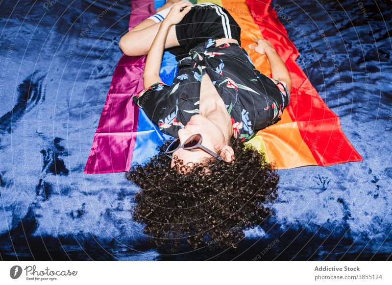 Entspannte Frau liegend auf LGBT-Flagge auf dem Bett gleich Regenbogen Fahne Homosexualität Respekt Toleranz auf den Kopf gestellt rechts Gemeinschaft