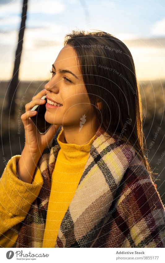 Entzückte Frau spricht auf Smartphone bei Sonnenuntergang Herbst Park sprechen reden sich[Akk] entspannen genießen Wochenende Funktelefon Lächeln Gespräch