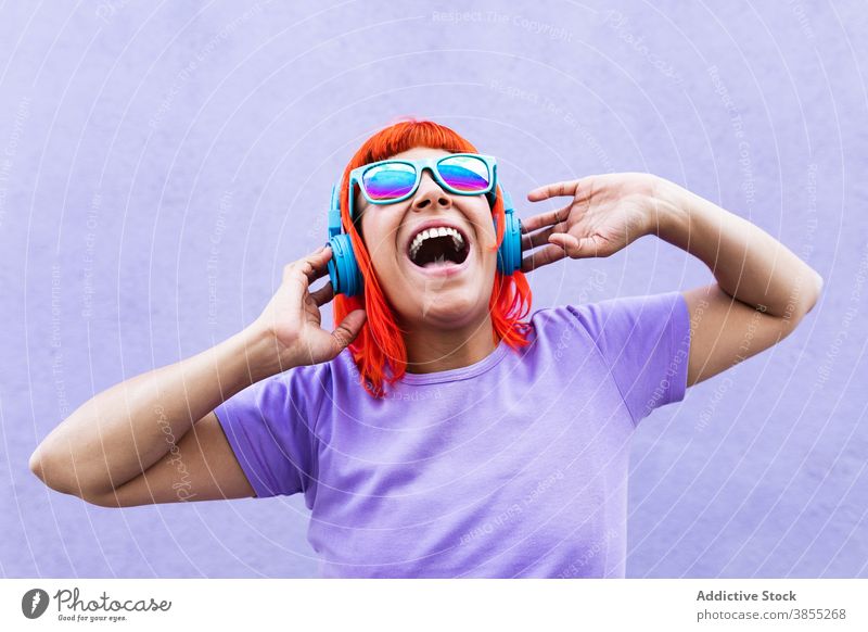 Aufgeregte rothaarige Frau beim Hören von Musik zuhören Zeichen Glück Straße Großstadt auflehnen farbenfroh hell Erwachsener tausendjährig laut schreien