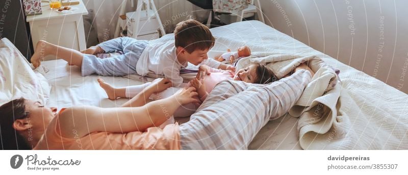 Entspannte Mutter und Söhne spielen über dem Bett. covid-19 Einsperrung Familie Kind Spielen panoramisch Panorama Lachen heiter Lächeln Fröhlichkeit Coronavirus