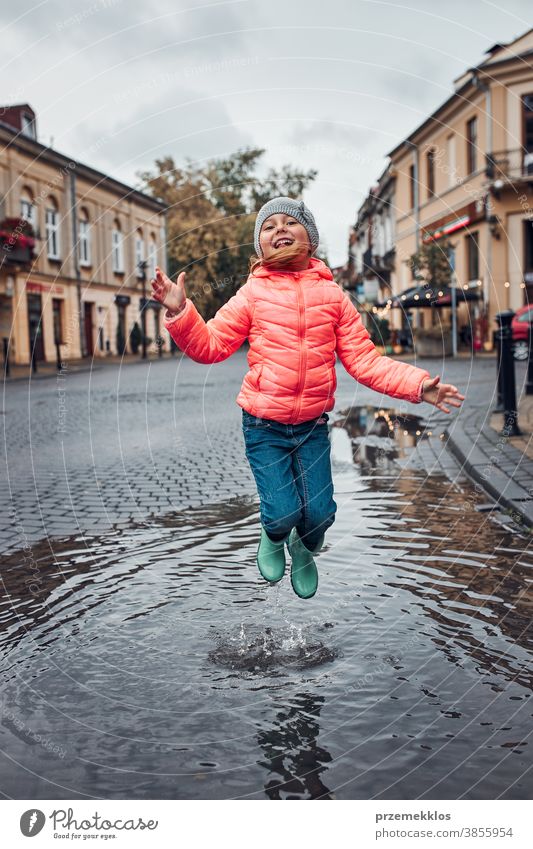 Kleines Mädchen springt an einem verregneten, düsteren Herbsttag in die Pfütze im Freien wenig saisonbedingt fallen Kindheit schön regnerisch Wetter außerhalb