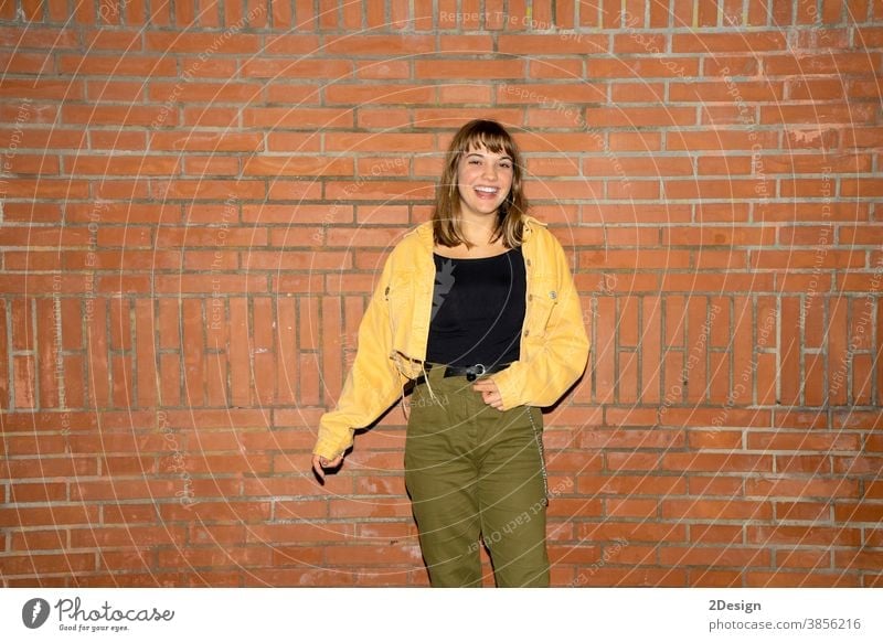 Hübsche junge Frau steht nachts an einer alten Ziegelmauer in der Stadt Stehen attraktiv Lächeln Glück Wand Baustein Freizeitkleidung Person schön Lifestyle