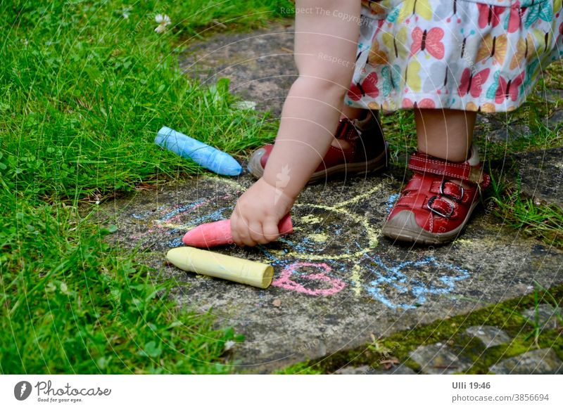 Kind bemalt einen alten Gartenweg farblich passend zum Kleidchen....... kindlich Sommertag Steinplatten zeichnen Buntstifte blau rot Gras Grünfläche Kleinkind