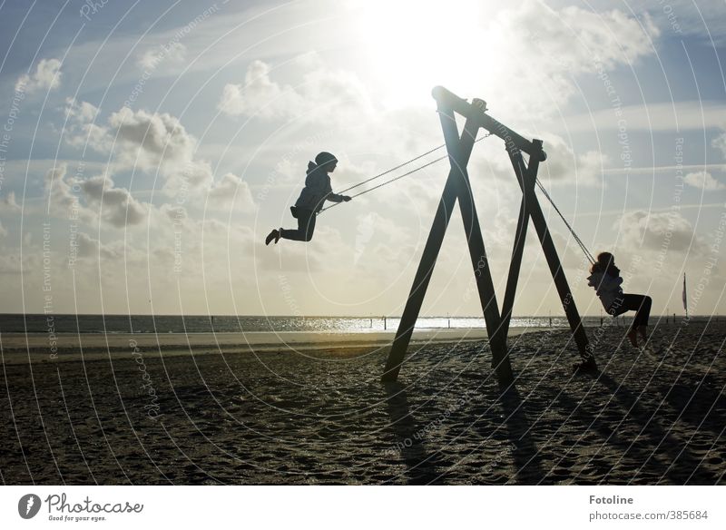 Zwei Mädchen schaukeln am Strand von Norderney dem Himmel entgegen. Mensch Kind Kindheit Umwelt Natur Landschaft Sonne Küste Nordsee Glück hell natürlich