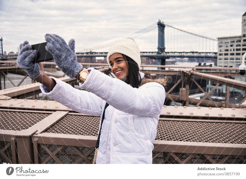 Lächelnde ethnische Frau nimmt Selfie in der Stadt Smartphone Großstadt warme Kleidung Oberbekleidung Saison heiter Selbstportrait benutzend schwarz