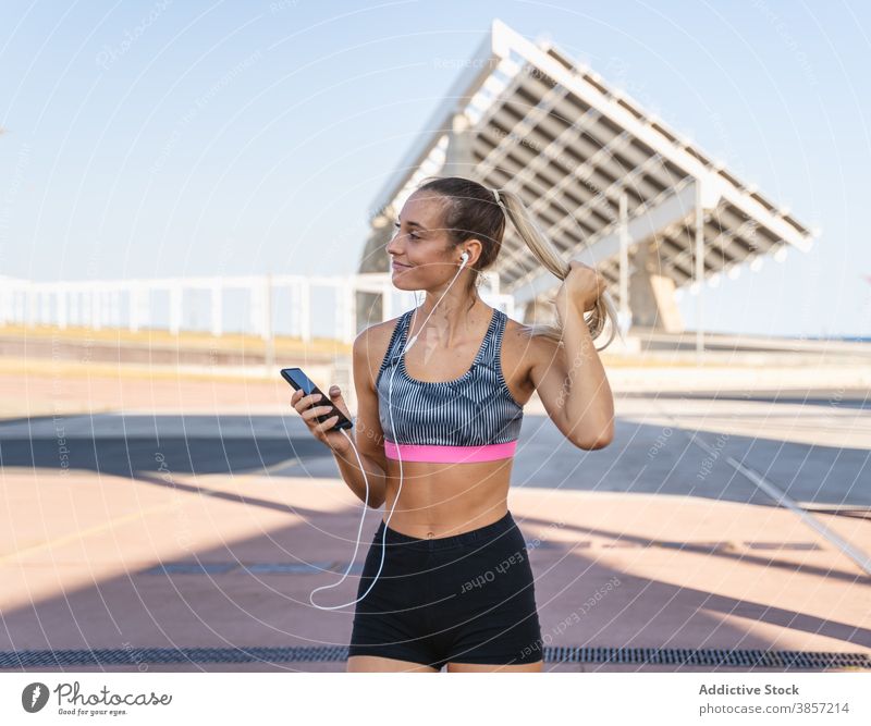 Fröhliche Sportlerin beim Musikhören im Kopfhörer zuhören Training Frau Smartphone genießen Sommer Großstadt Athlet schlank Gesundheit Fitness Glück sportlich