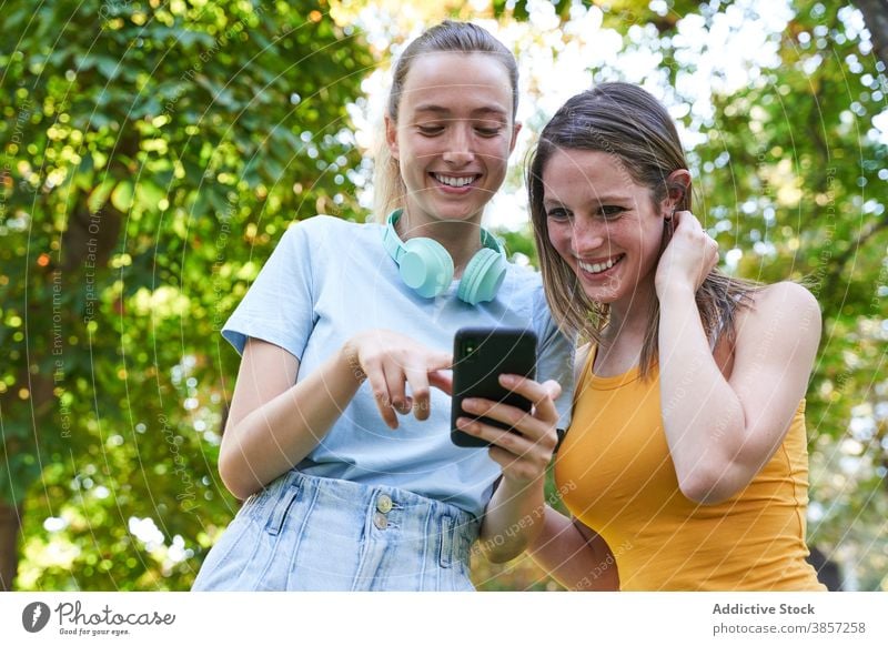 Weibliche Hipster mit Smartphone beim Spaziergang in der Stadt Freundin benutzend diskutieren Straße teilen Zusammensein Mobile Telefon heiter Lachen Mädchen