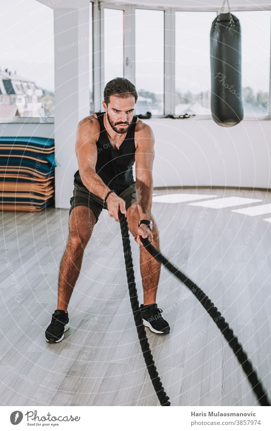 Mann trainiert mit Seilen in der Turnhalle abdominal Bauchmuskeln Erwachsener Athlet sportlich attraktiver Mann Bizeps Bodybuilding Kaukasier Truhe