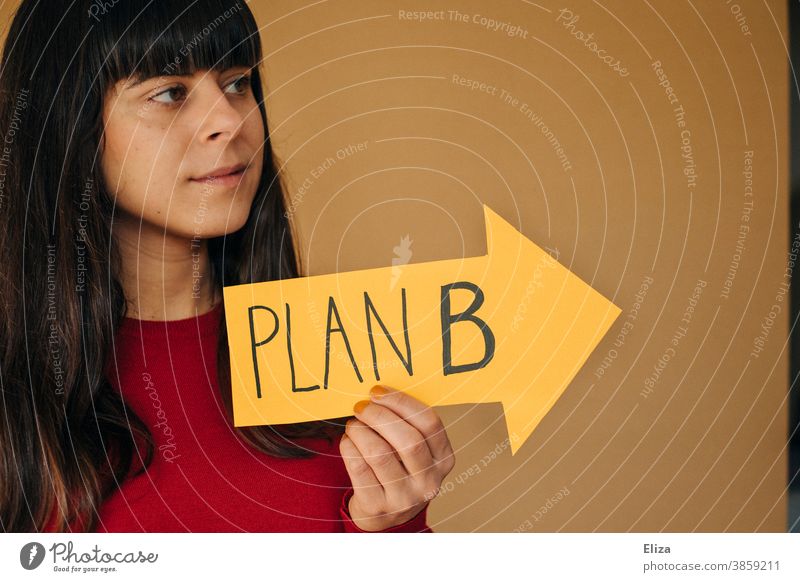 Eine junge Frau hält einen gelben Pfeil mit der Aufschrift PLAN B. Alternativer Lebensweg. Plan B Richtung Lösung planen Business Ausbildung Zweiter Bildungsweg