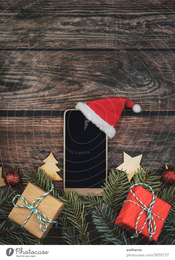 Hintergrund des Weihnachtskonzepts: Smartphone mit Weihnachtsmannhut und Weihnachtsbaumzweigen Weihnachten Weihnachtshintergrund Heiligabend Textfreiraum