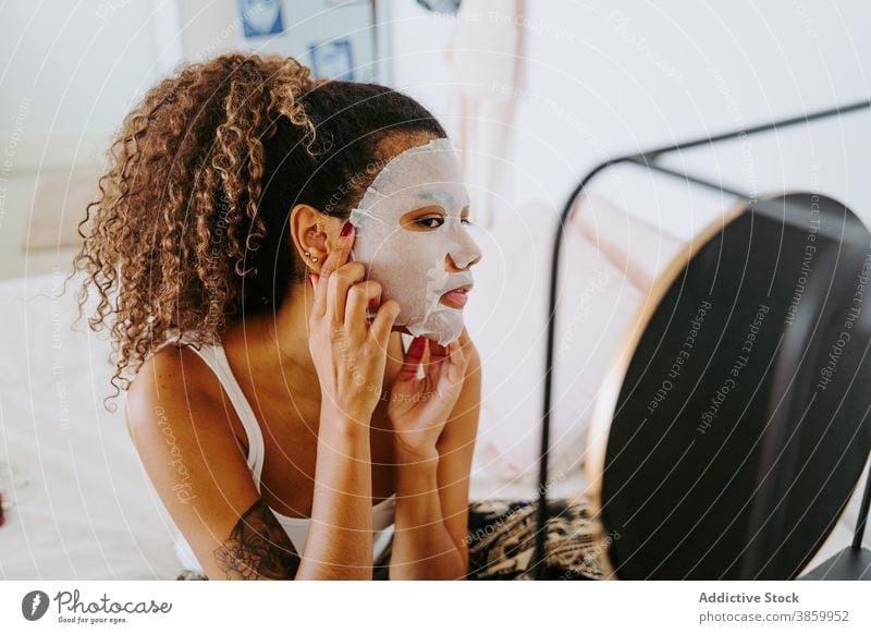 Frau Anwendung Gesichts kosmetische Maske in der Nähe von Spiegel Mundschutz bewerben Hautpflege Kosmetik Schönheit zu Hause Leckerbissen krause Haare