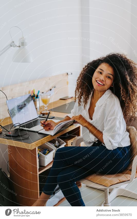 Ethnische Frau, die von zu Hause aus arbeitet Arbeit abgelegen freiberuflich Laptop zur Kenntnis nehmen schreiben modern Planer jung Afroamerikaner schwarz