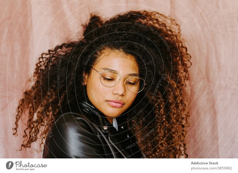 Stilvolle schwarze Frau in Lederjacke im Studio Afro-Look Frisur trendy lässig jung sorgenfrei ethnisch Afroamerikaner Outfit cool modern stehen Jacke Mode