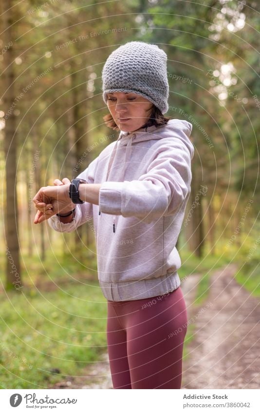 Weibliche Läuferin überprüft Armbanduhr im Wald während des Trainings Fitness Tracker Frau prüfen Handgelenk Zeit Puls intelligente Uhr Wälder Sportbekleidung