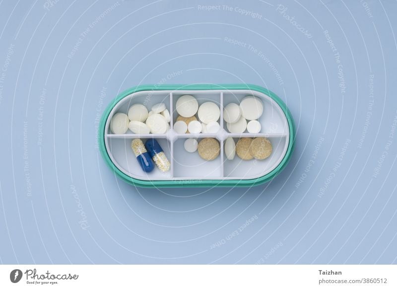 Tägliche Pillenschachtel mit medizinischen Pillen auf blauem Hintergrund. Ansicht von oben. Flach liegend Medizin Tag Organisator Gesundheitswesen Hinweis