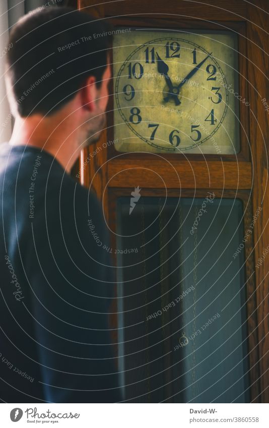 Mann schaut auf eine Standuhr und liest die Zeit ab Uhr Planung Uhrenzeiger Ziffern & Zahlen Vergänglichkeit Eile Stress Nostalgie