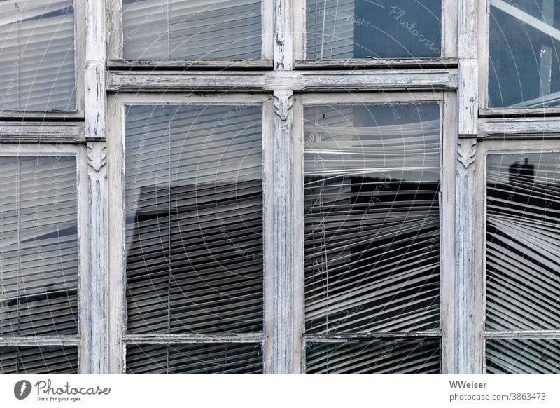 Hinter diesem Fenster rührt sich schon lange nichts mehr Fensterrahmen verwittert alt verziert Jalousie schräg kaputt Glas Spiegelung verlassen lost place