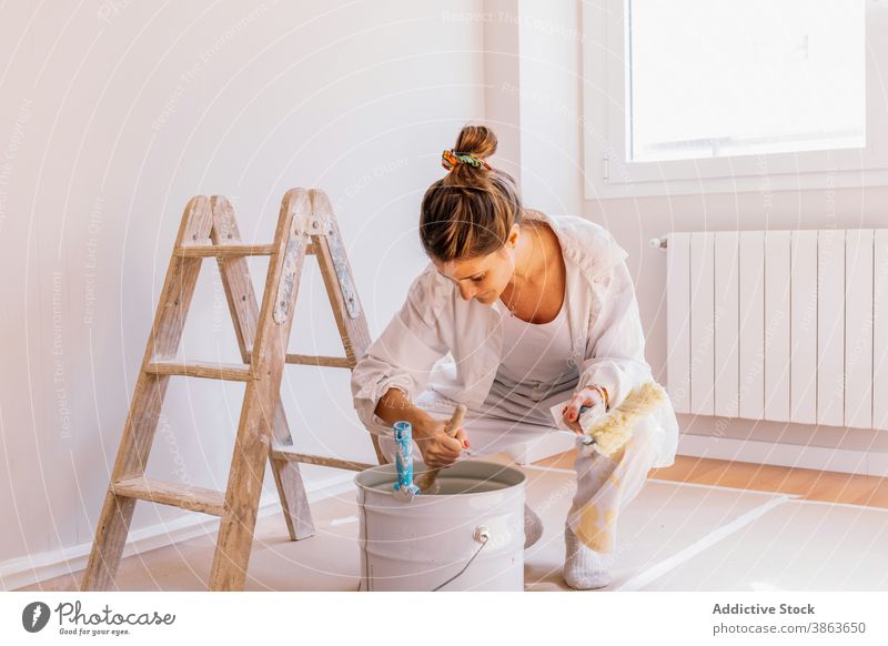 Fröhliche Frau beim Vorbereiten der Farbe während der Renovierung Eimer renovieren heimwärts Lächeln Pinselblume Wand vorbereiten Appartement jung Glück Bürste