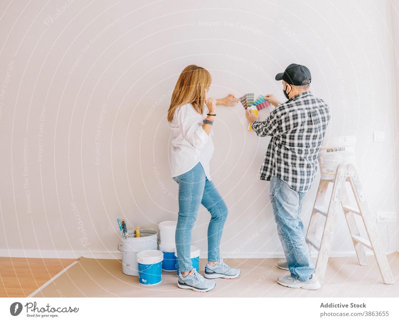 Frau und Mann in Masken wählen Farben der Wände im Zimmer renovieren Appartement Palette Wand Papier pflücken Prozess Arbeit Design heimwärts Job Arbeiter