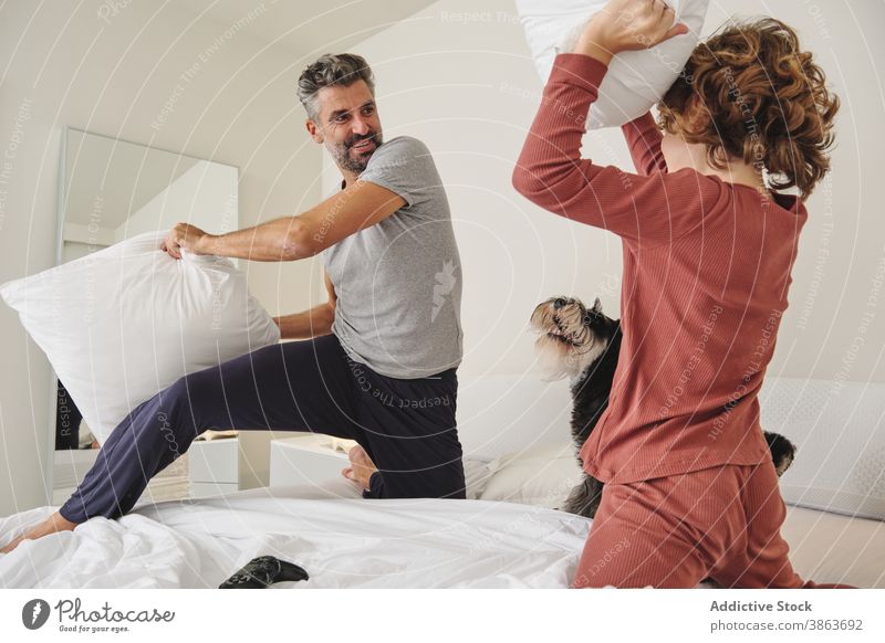 Sorgloser Mann und Junge springen auf dem Bett während Kissenschlacht Kopfkissen kämpfen Spaß haben Vater Sohn Zusammensein spielen Spiel sorgenfrei heimwärts