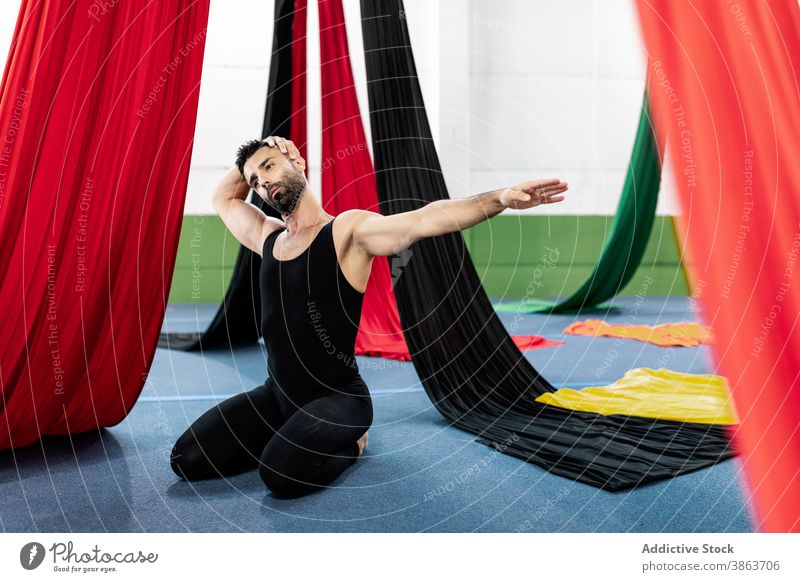 Männlicher Tänzer streckt den Hals in der Nähe von Luftseiden Mann Dehnung Aufwärmen Probe Atelier Seide Antenne Neigung beweglich männlich Erwachsener