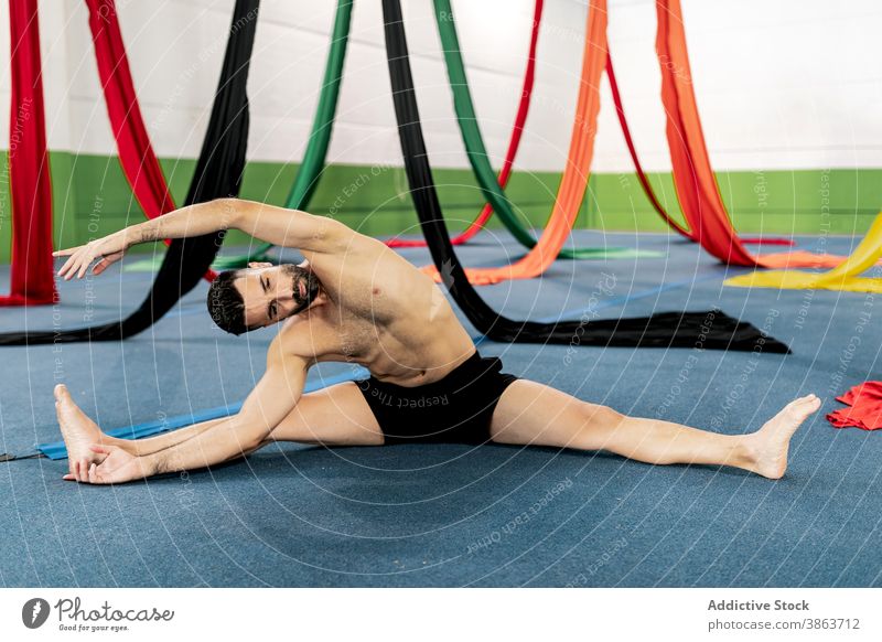 Männlicher Tänzer streckt sich in der Nähe von Luftseiden Mann Dehnung Stock Seide Antenne Atelier beweglich gymnastisch vorbereiten Probe männlich Bändchen